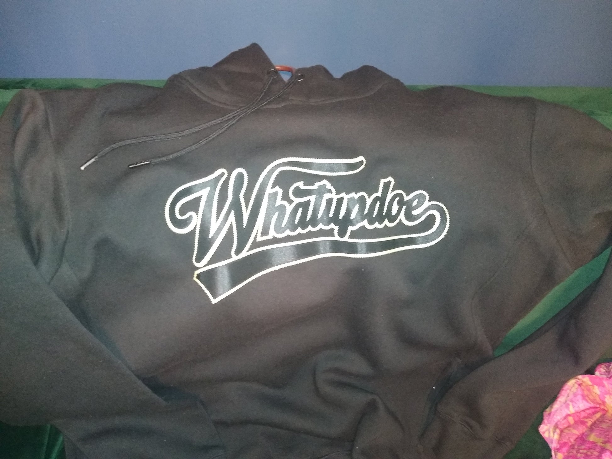 Black hoodie with 'Whatupdoe' logo on black and gold heat transfer. Simulated two layer stitching to look like embroidery, using Stahl's Sim Stitch twill heat transfers.